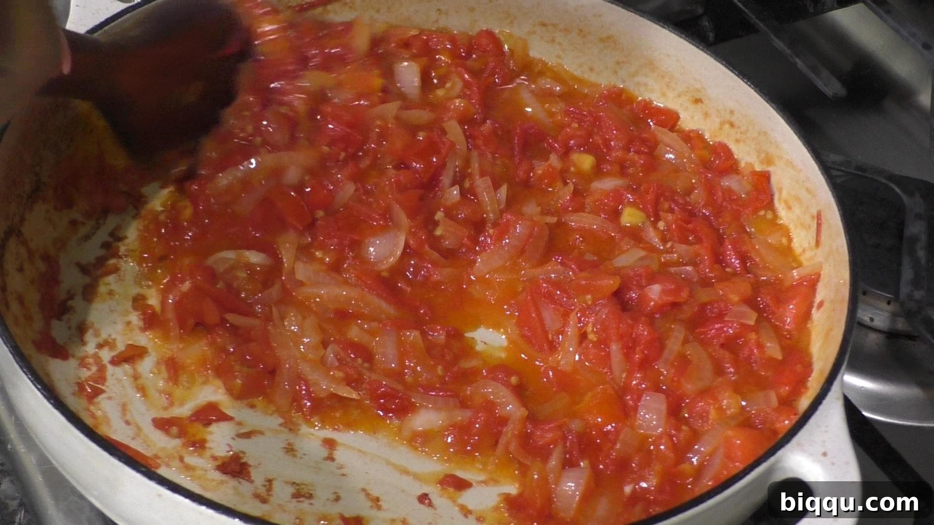 Diced tomatoes and onions cooking in a pot, simmering to create a rich, flavorful base for the stew.