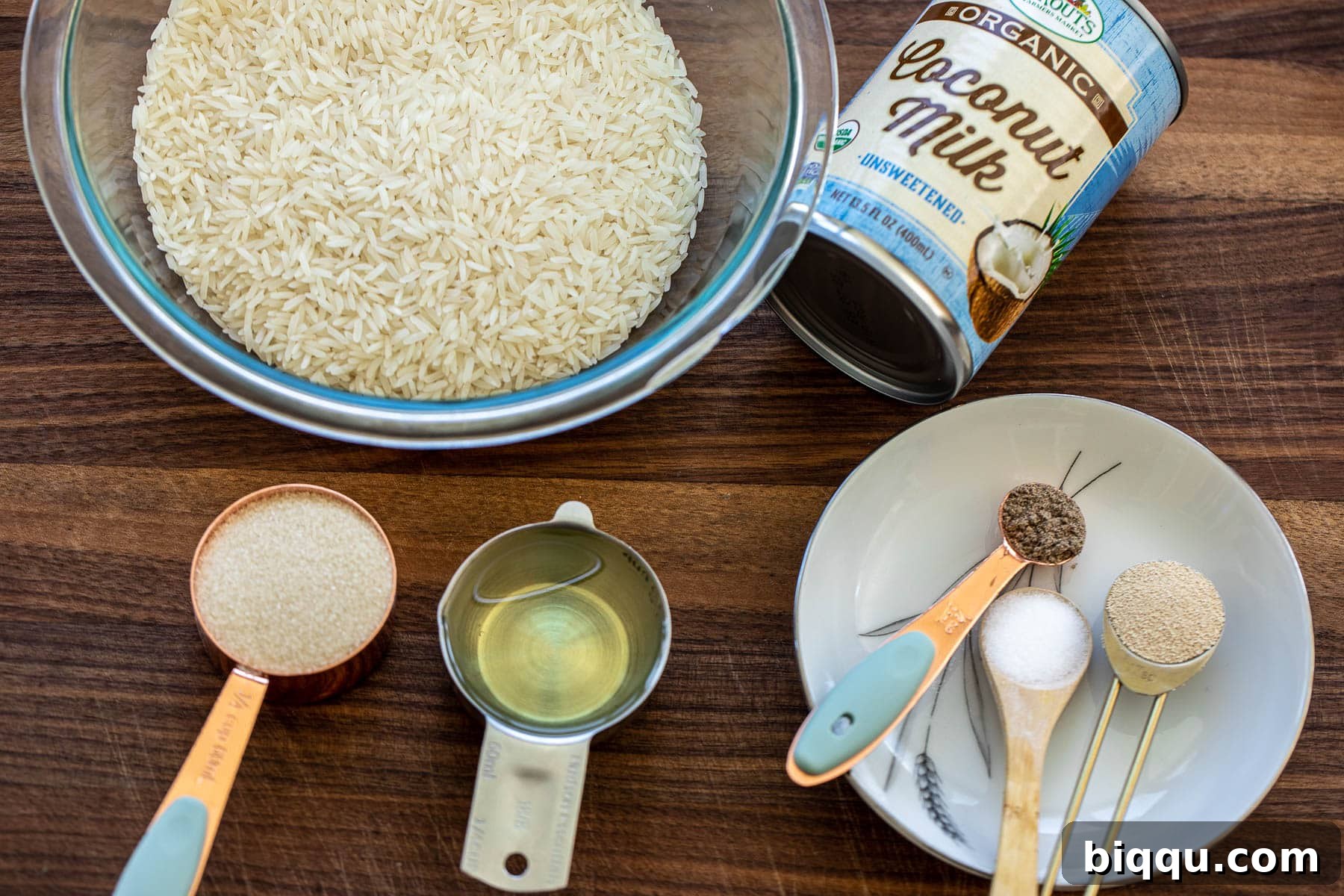 Various ingredients for Vitumbua laid out on a wooden chopping board, including rice, coconut milk can, sugar, and spices.