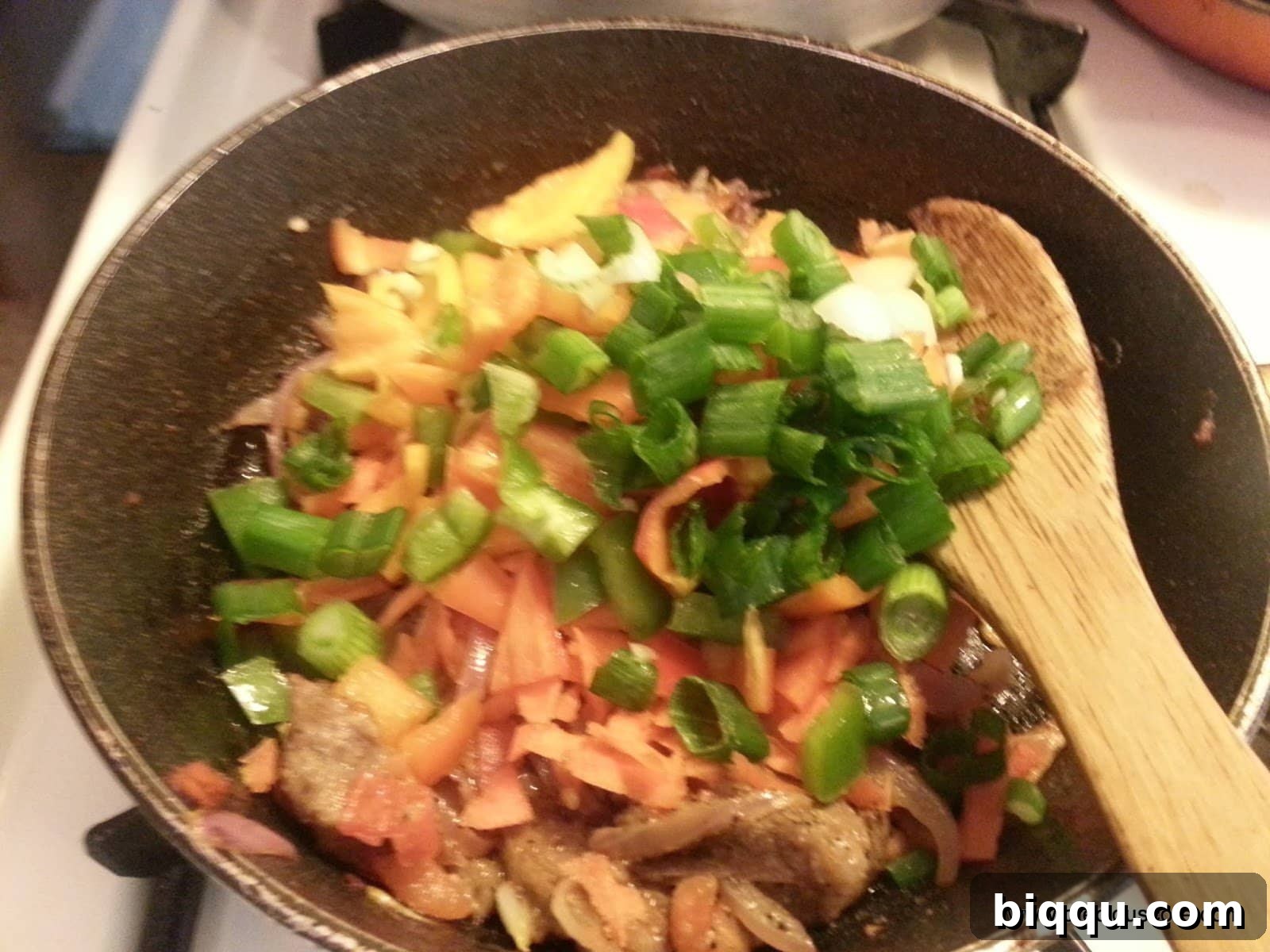 Meat and mixed vegetables added to the pan, stirring