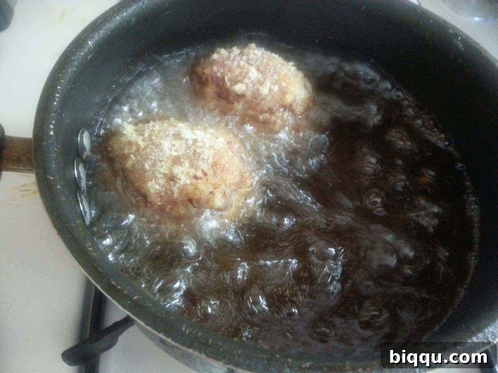 Scotch Eggs sizzling and deep-frying in hot oil, achieving a perfect golden crisp.