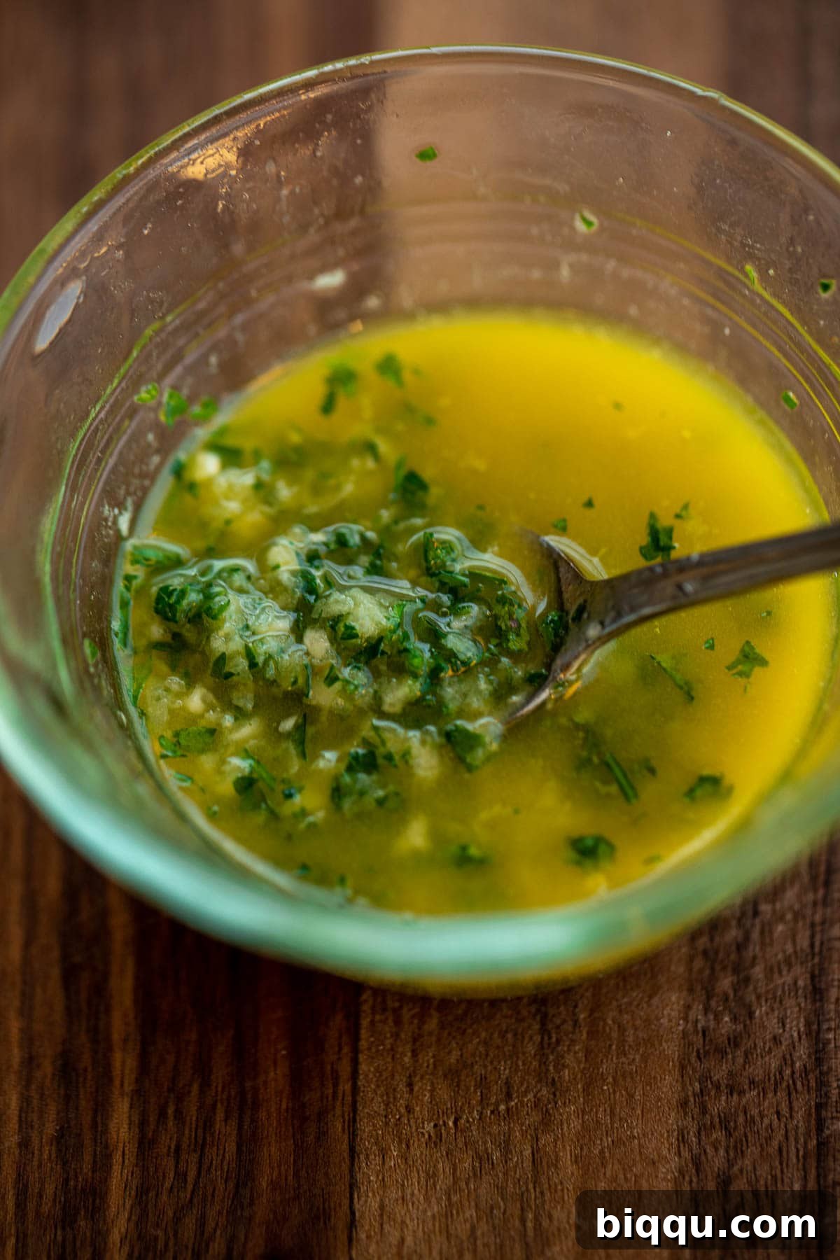 Ingredients for garlic butter – minced garlic, melted butter, and parsley – mixed in a small bowl.