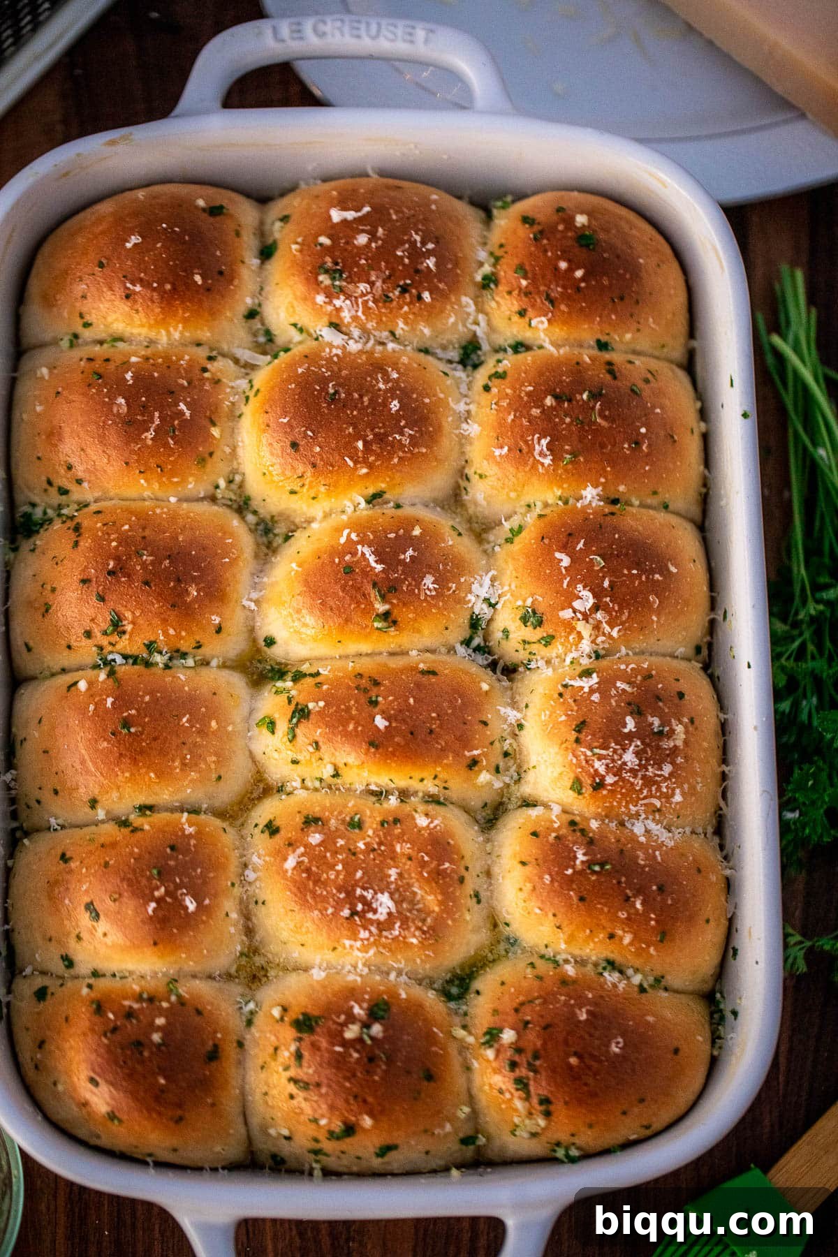 Garlic Butter rolls in a baking dish, adorned with grated parmesan cheese and fresh parsley.