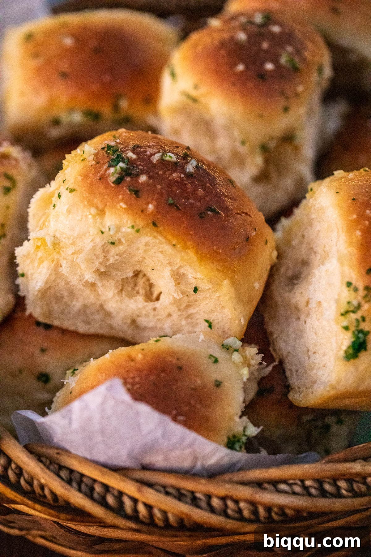Freshly baked and brushed garlic butter rolls served in a rustic bread basket.