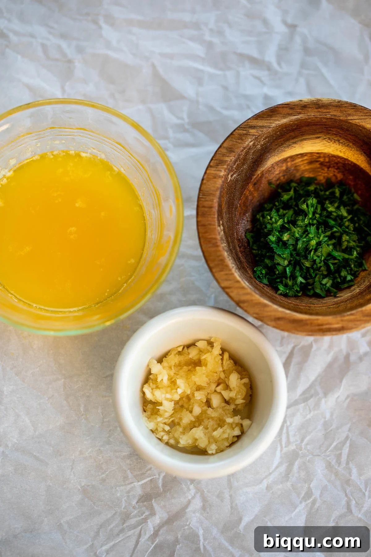 Ingredients for the garlic butter topping: minced garlic, melted butter, and fresh minced parsley.