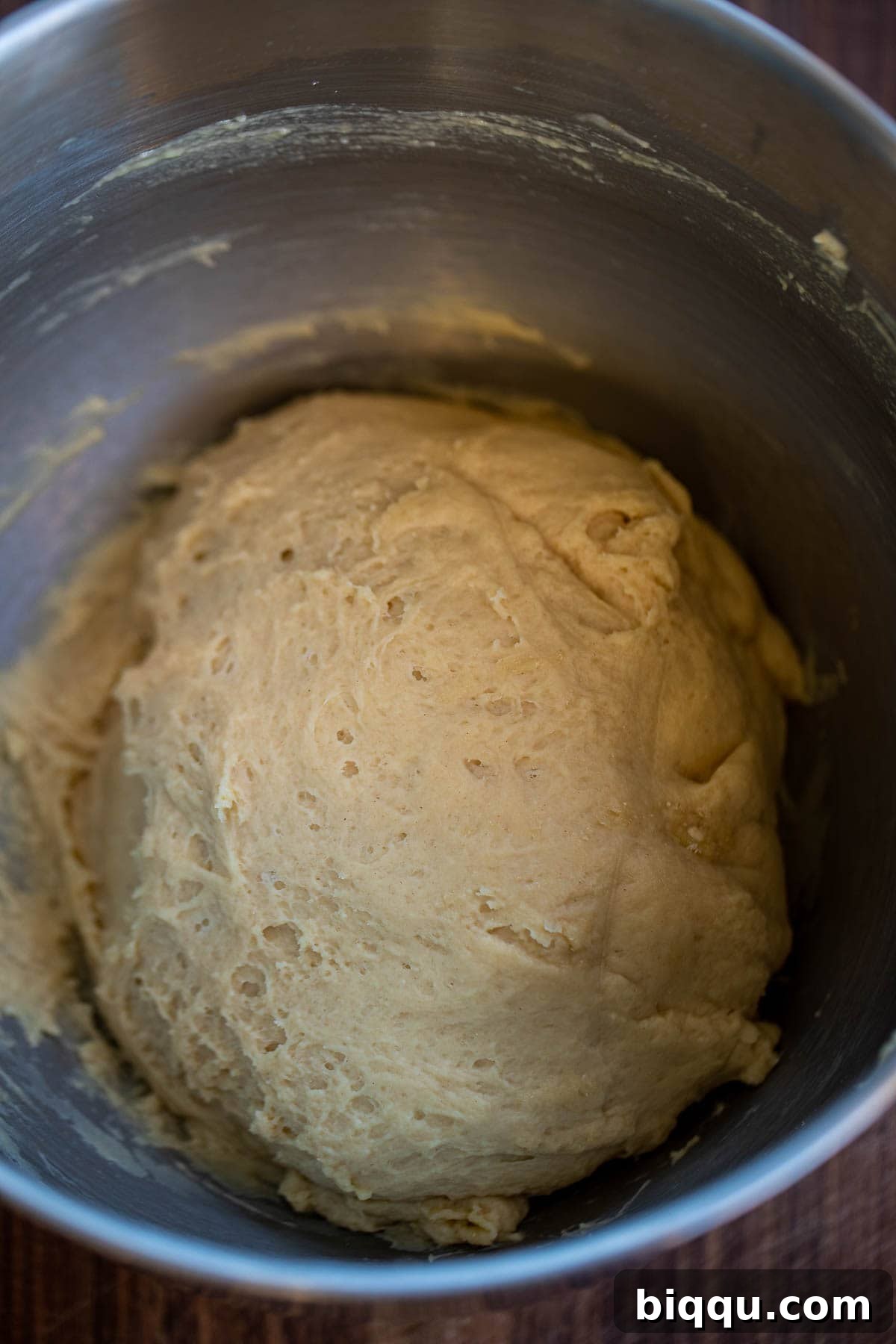 Bread dough mixing in a stand mixer bowl.