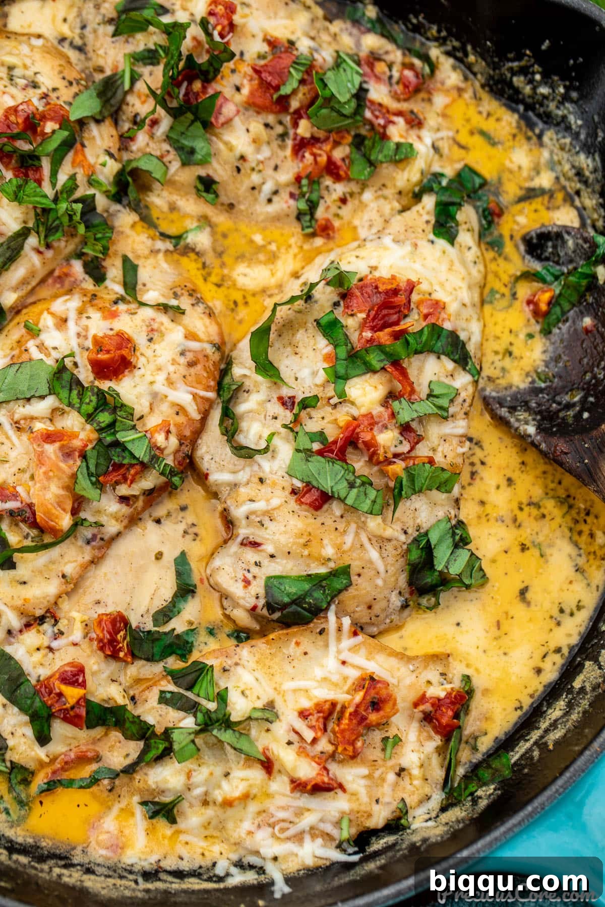 Close-up shot of a pan filled with beautifully cooked chicken breasts simmering in a thick, creamy sun-dried tomato sauce.