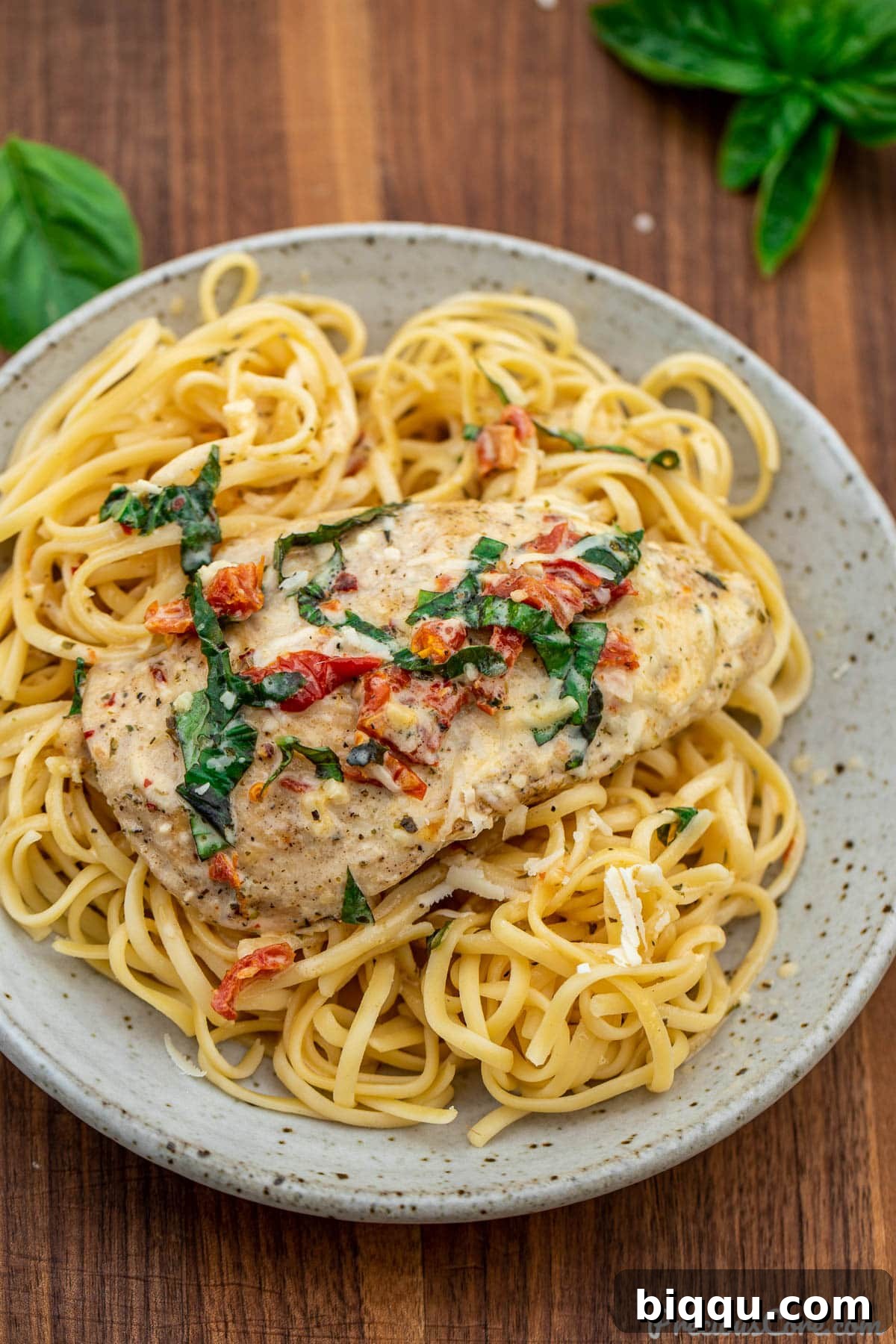 A serving of Marry Me Chicken generously plated over linguine pasta, garnished with fresh basil.