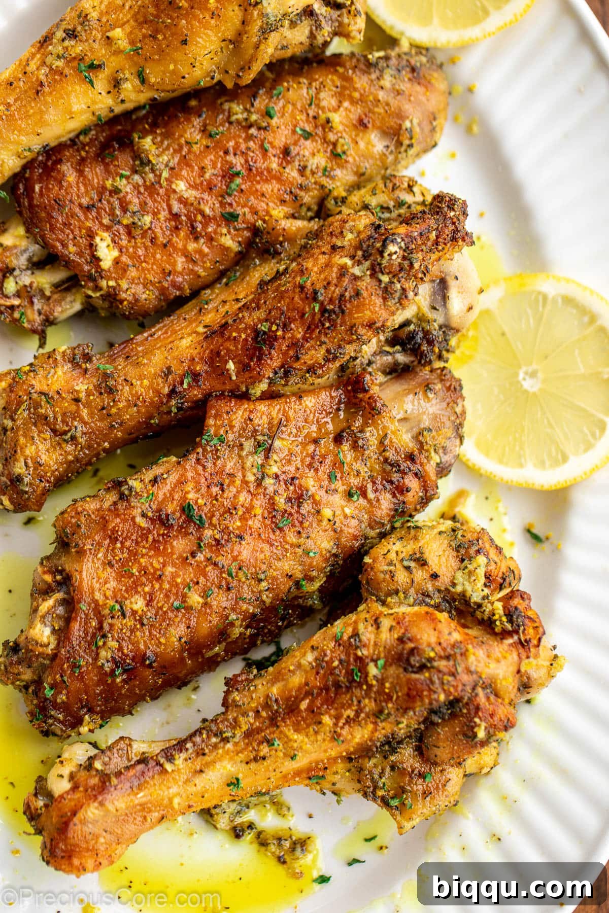 Crispy and golden lemon pepper turkey wings beautifully arranged on a serving platter, garnished with fresh lemon slices.