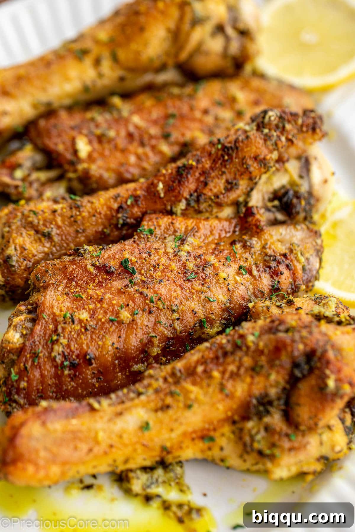 Close-up shot of perfectly cooked, golden-brown turkey wings glistening with lemon pepper sauce.