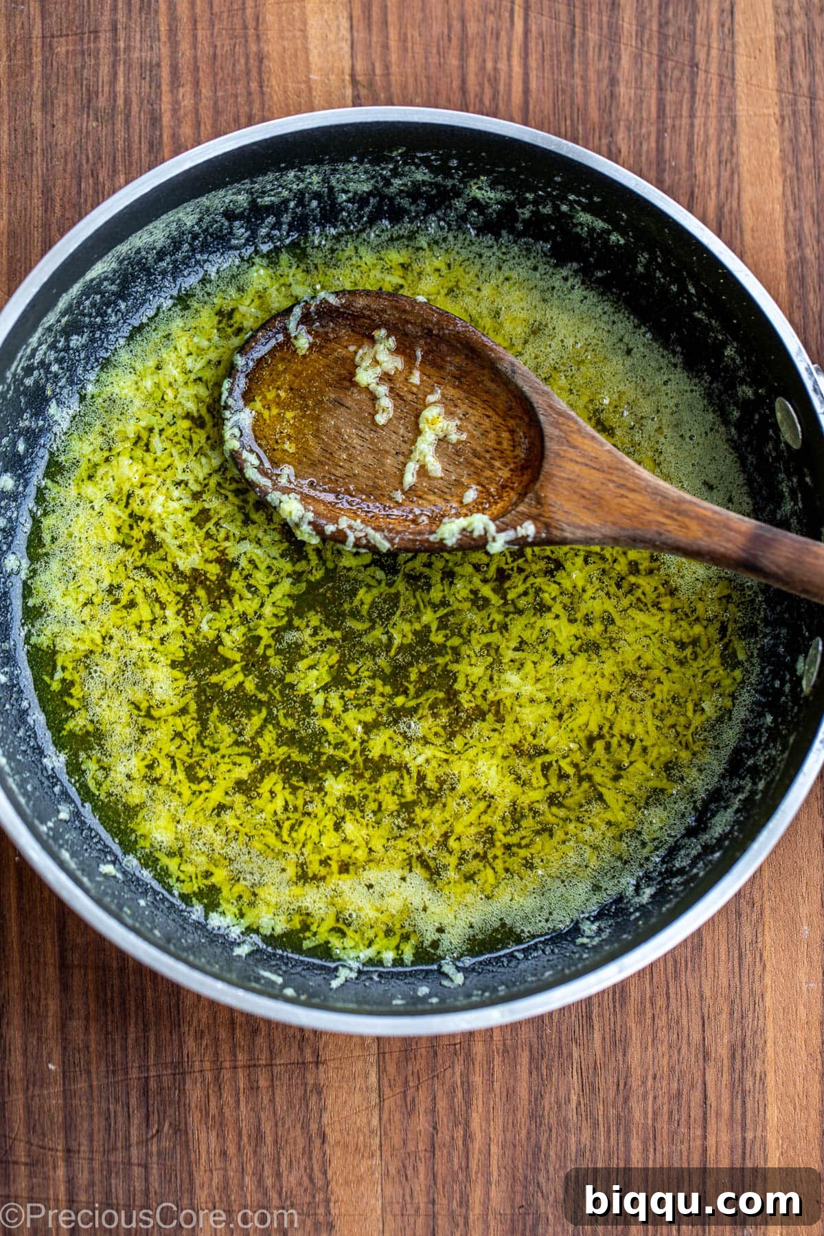 A small skillet containing melted butter, minced garlic, and lemon pepper seasoning, forming the savory sauce.