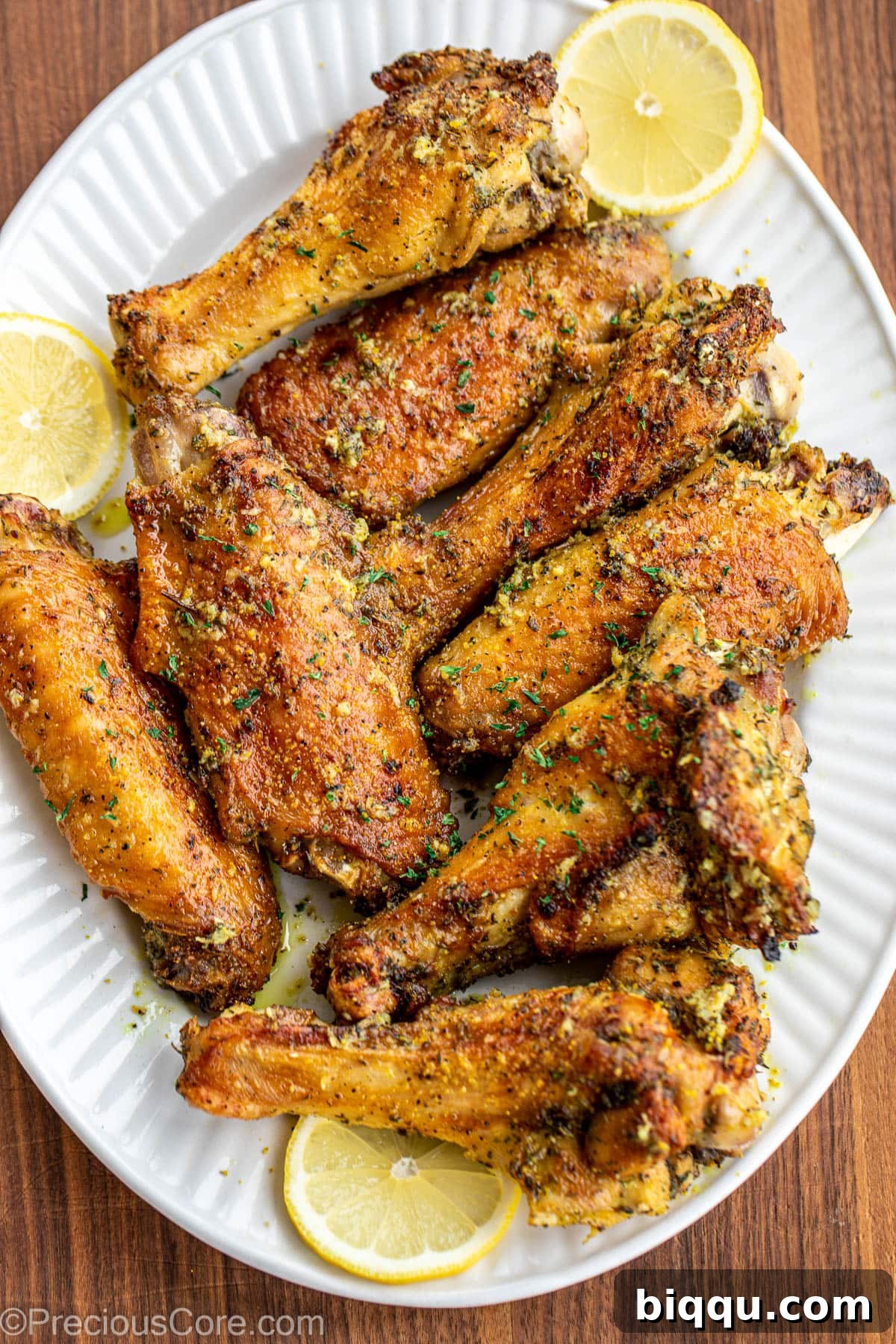 Finished Lemon Pepper Turkey Wings piled high on a serving platter, garnished with fresh herbs and lemon slices.