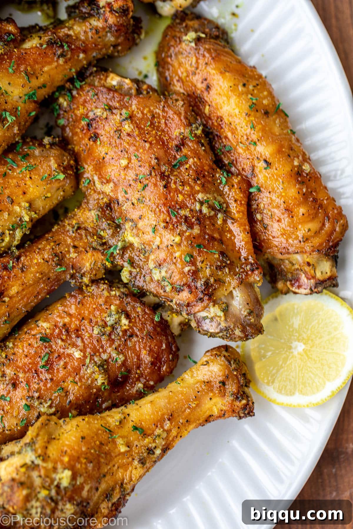 A close-up of a platter of baked lemon pepper turkey wings, elegantly garnished with lemon slices and fresh parsley.