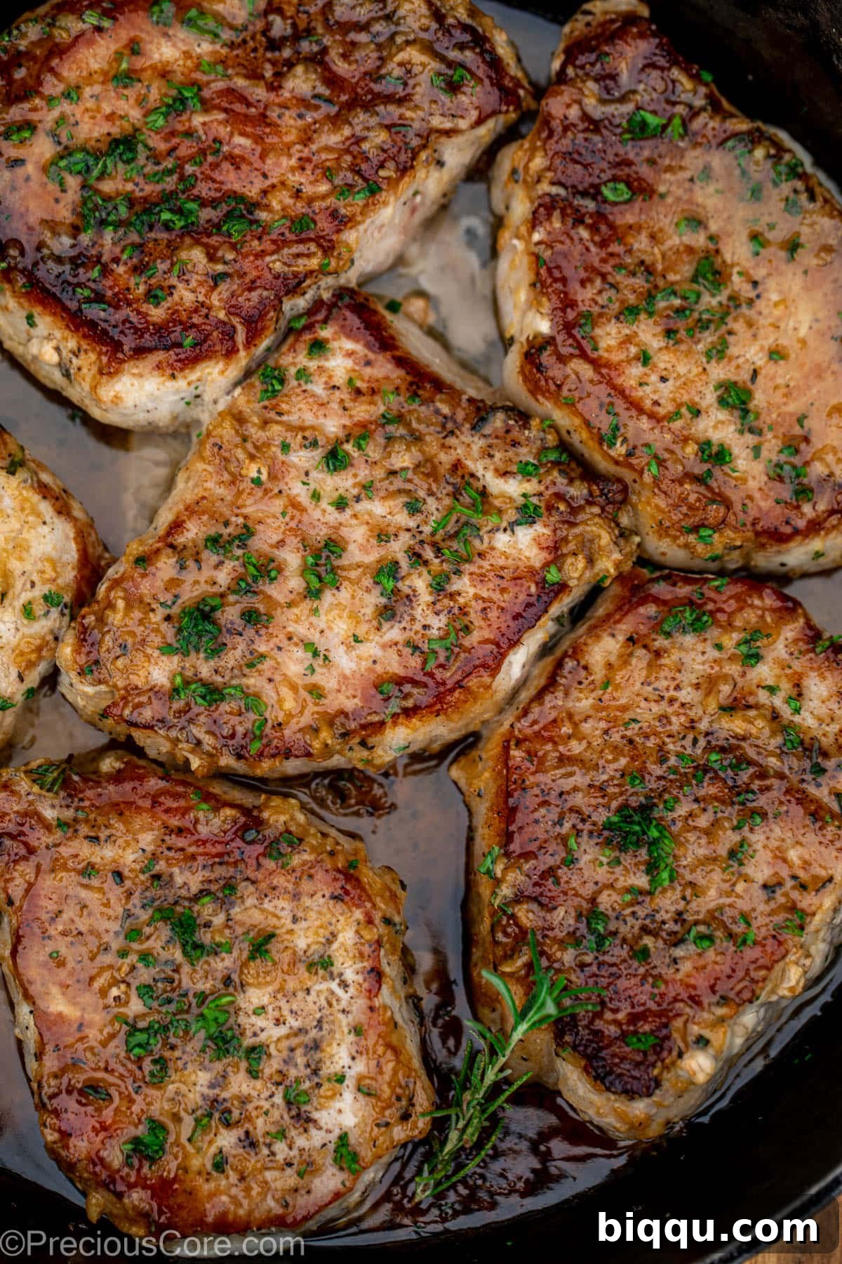Pan seared boneless pork chops in a cast iron pan with butter underneath.