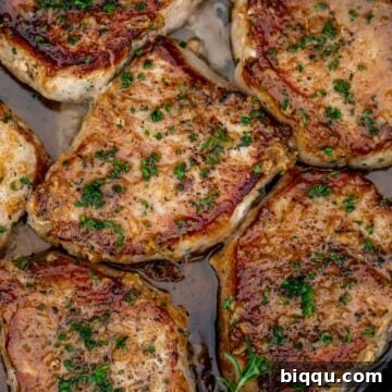 Pan seared boneless pork chops in a cast iron pan with butter underneath.