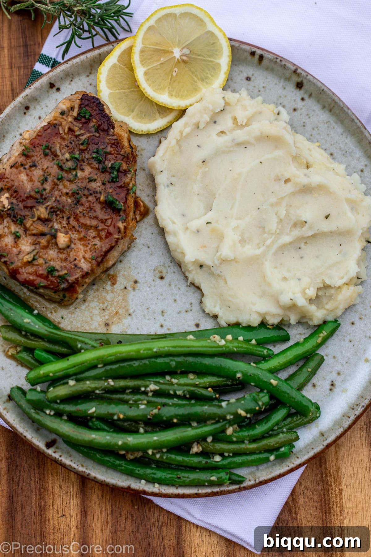 Cooked pork chops in a pan with green beans and mashed potatoes.