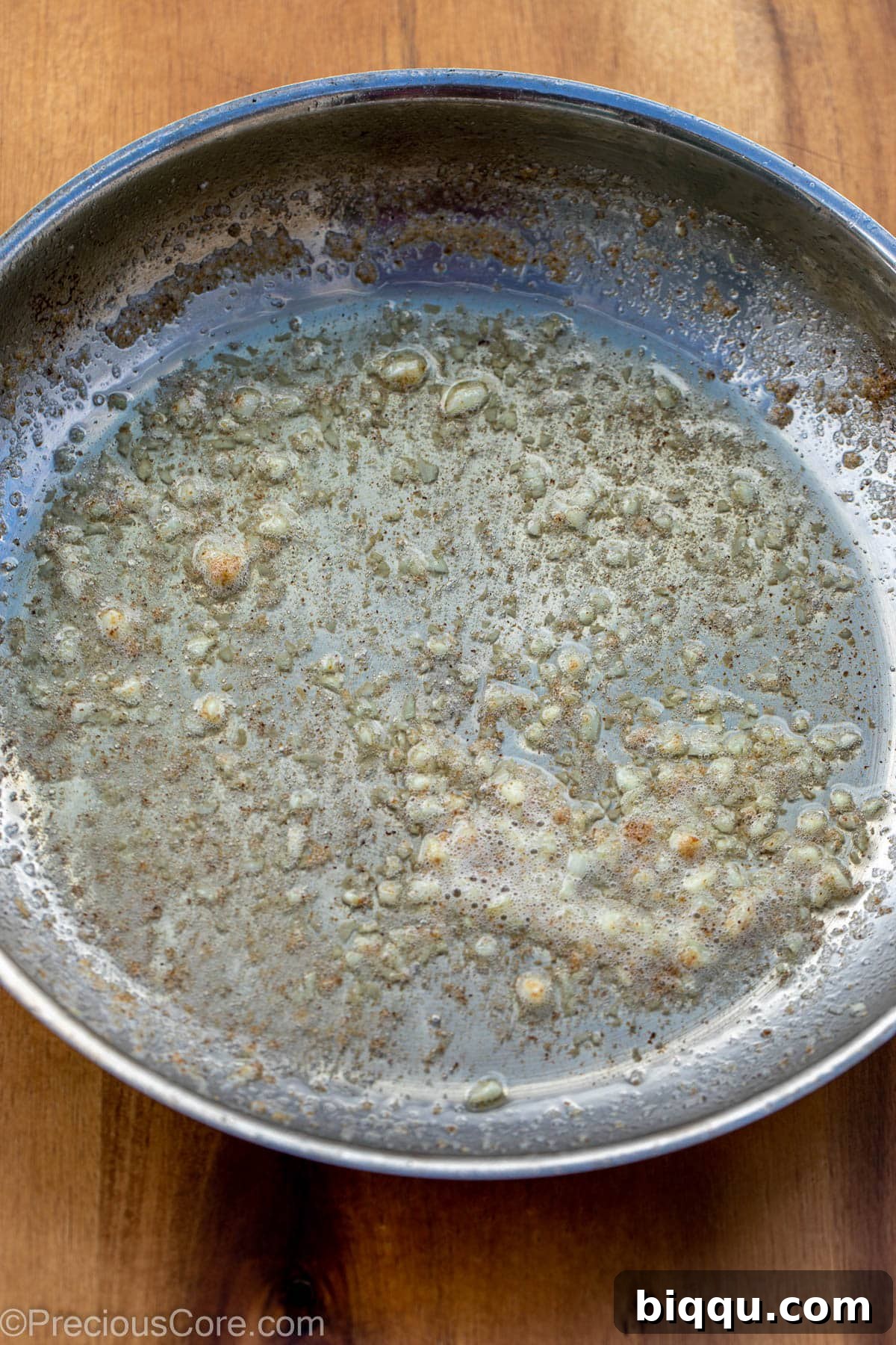 Finely minced garlic sizzling gently in melted unsalted butter in a large non-stick skillet.
