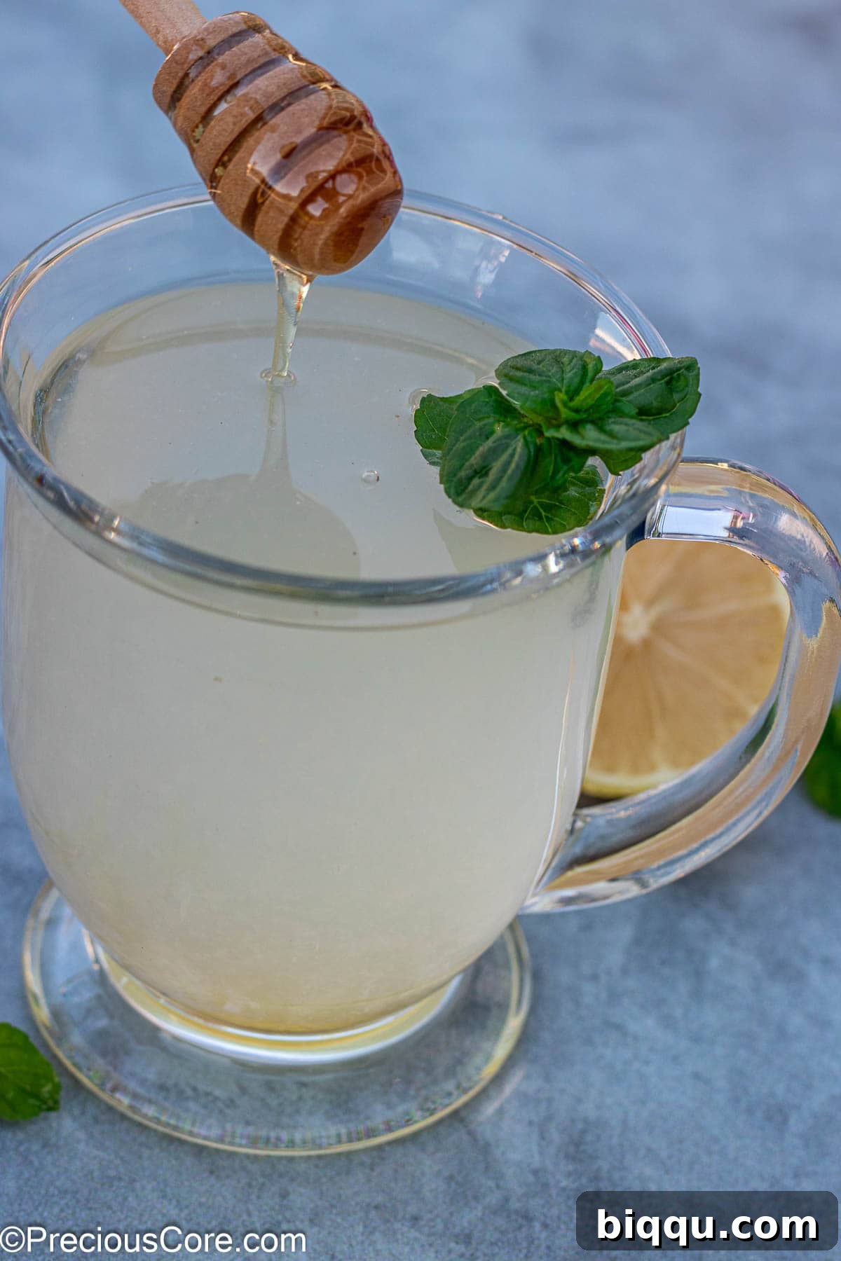 A close-up shot of a steaming mug of honey lemon tea, ready to be enjoyed, with a lemon slice garnish.