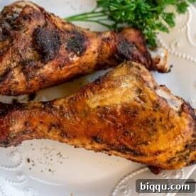Two perfectly golden and juicy Baked Turkey Drumsticks resting on a plate, ready to be devoured.