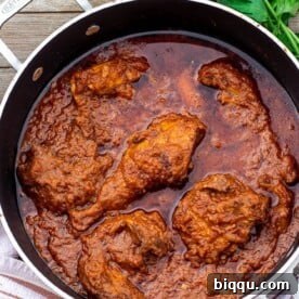 A large pan filled with rich, savory African Chicken Stew, garnished with fresh herbs and ready to serve.