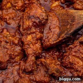 A close-up of a rich, red tomato chicken stew, simmering perfectly in a pot, representing the heart of African dinner cuisine.