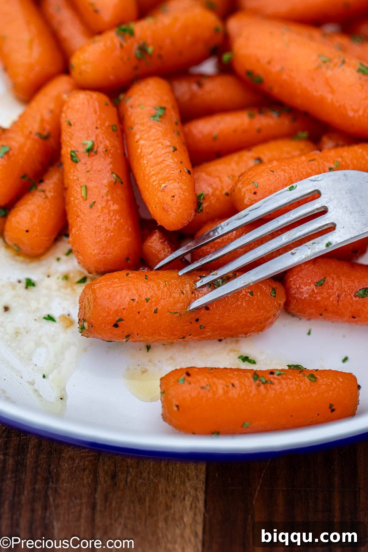 A fork piercing into a perfectly cooked, glazed carrot piece, highlighting its tenderness.