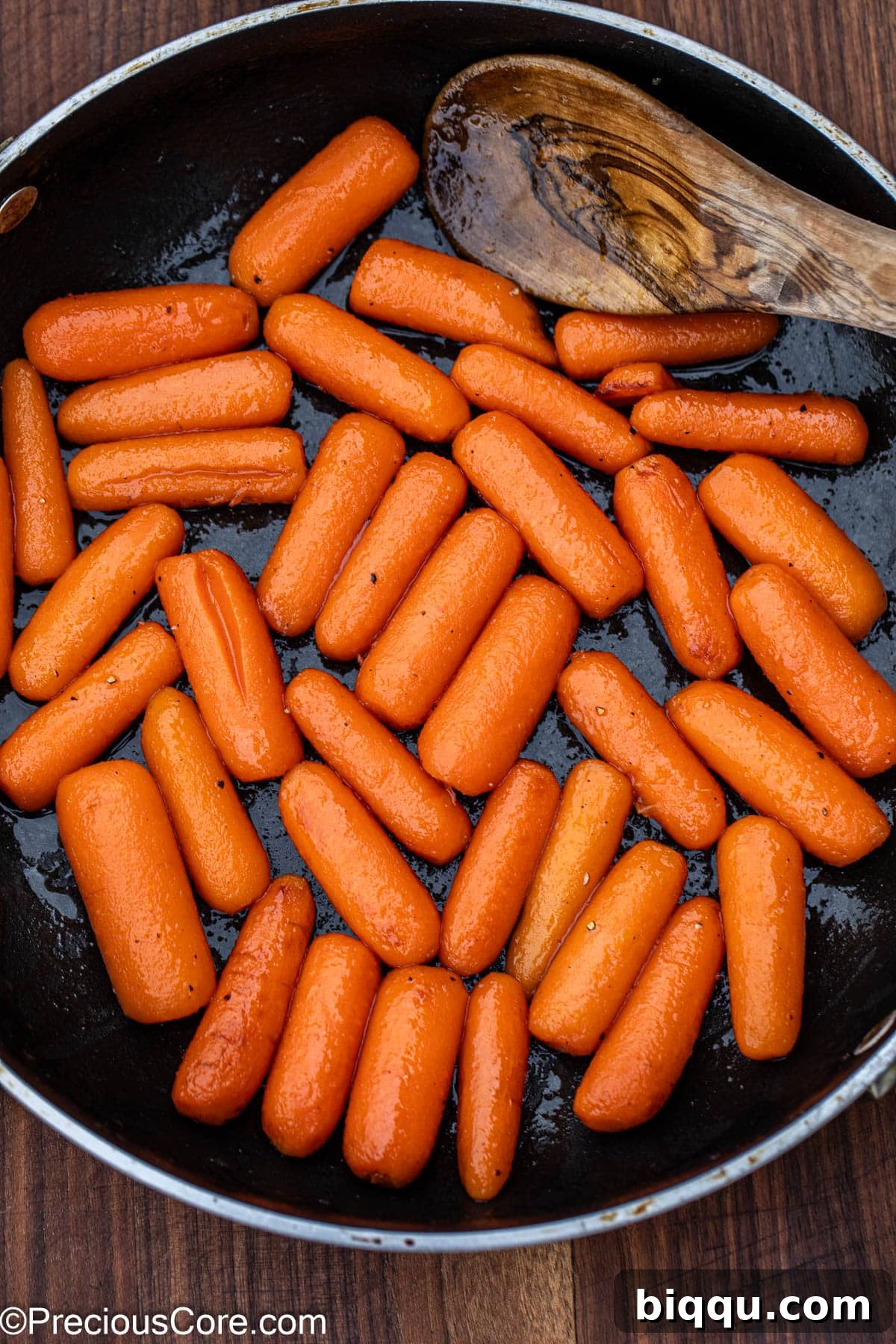 Honey glazed carrots simmering in a skillet, coated in a beautiful, reduced sauce.