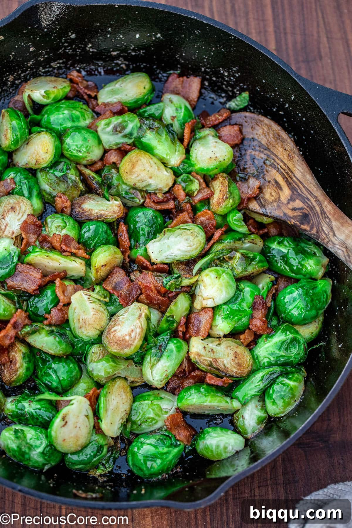 Pan-fried Brussels sprouts with bacon in a black skillet.