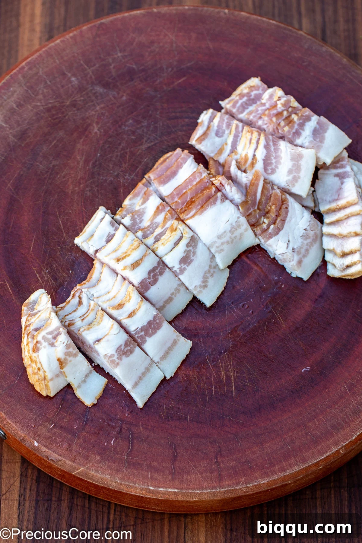 Sliced bacon on a round chopping board.