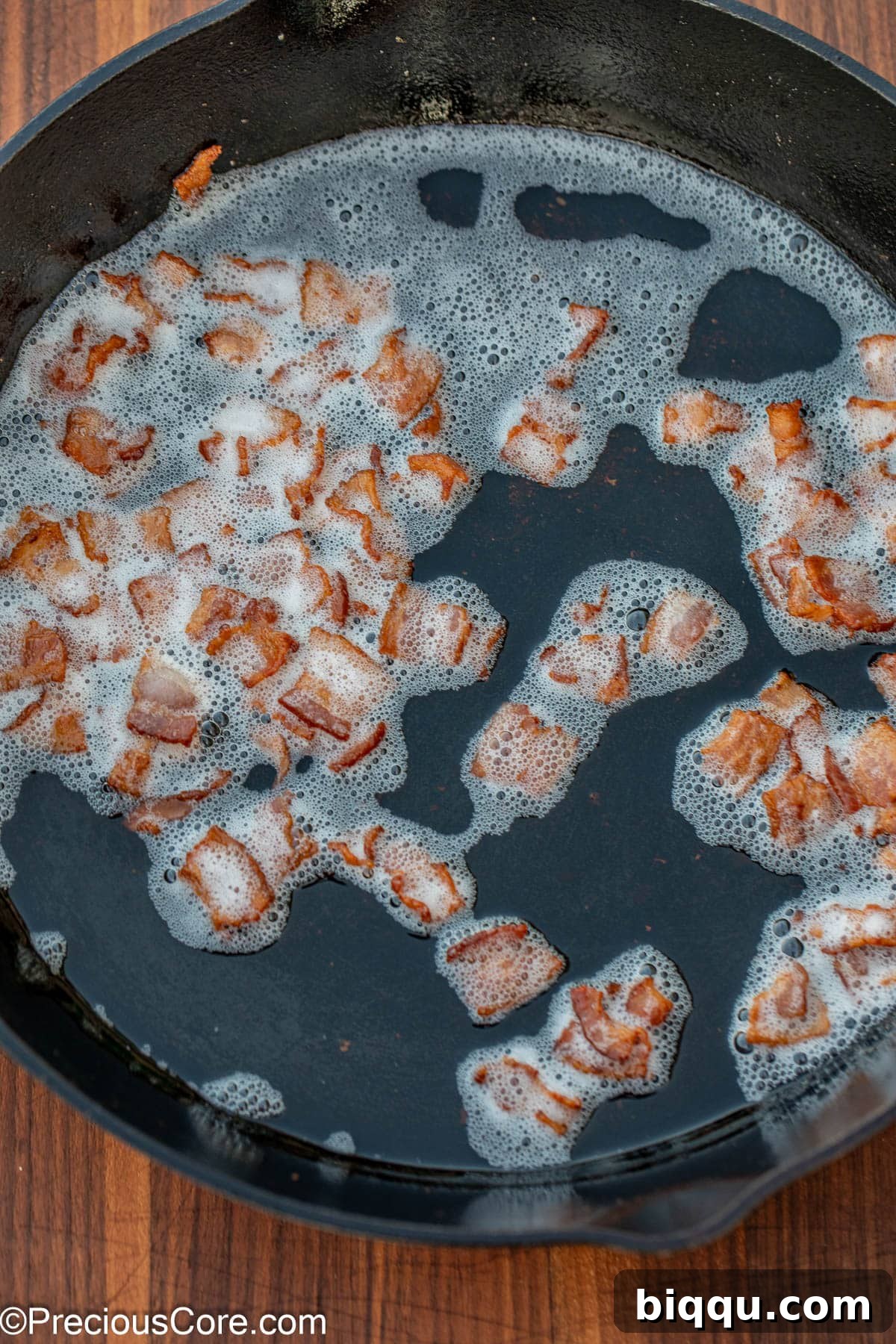 Browned bacon bits in bacon grease in a skillet.