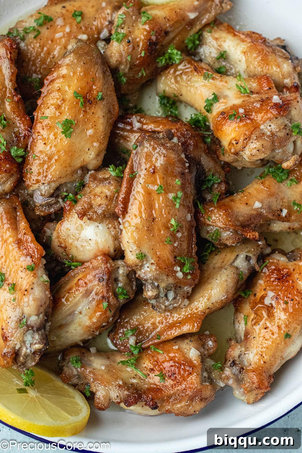 A generous serving of glistening Garlic Butter Wings in a white serving dish, ready to be enjoyed.