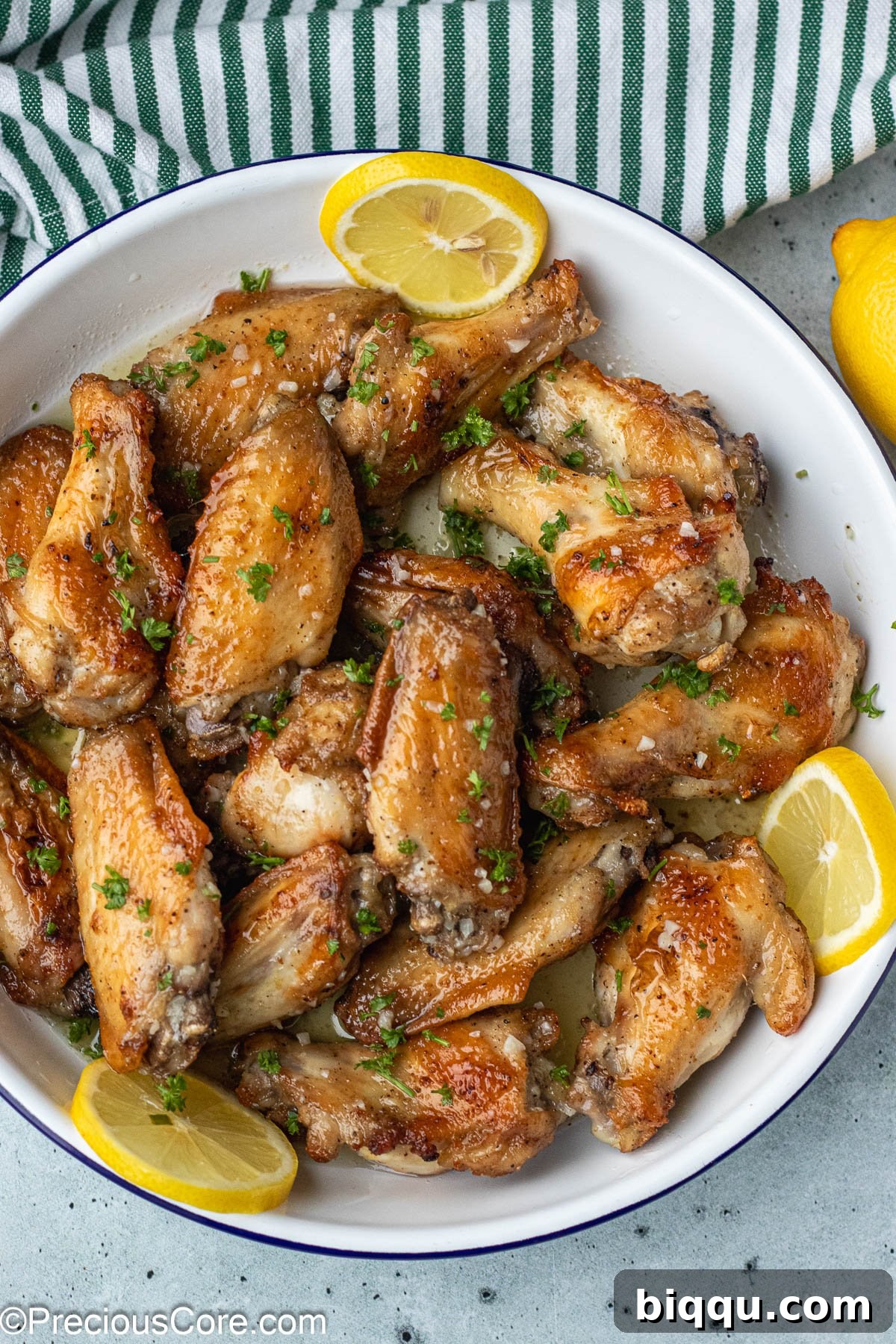 A close-up of a chicken wing beautifully garnished with vibrant minced parsley, showcasing its golden-brown skin.