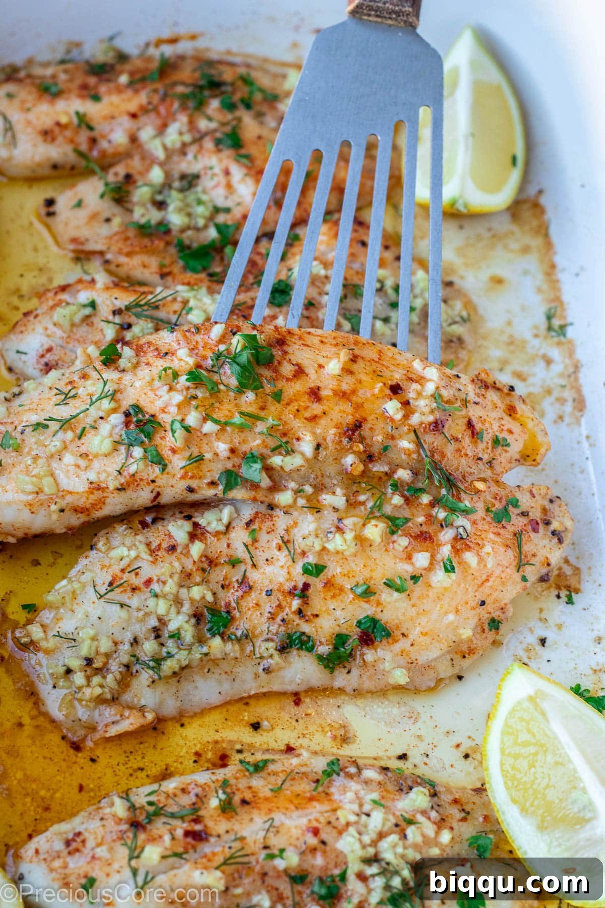 A single tilapia fillet generously topped with a dollop of fresh garlic butter, perfectly seasoned and ready for baking.