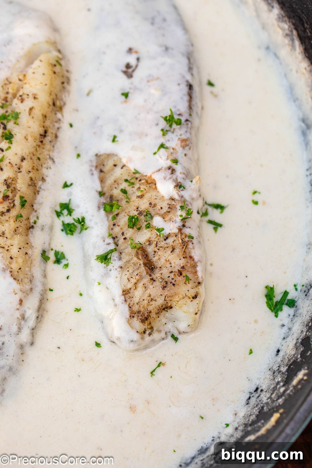 Silken Fish Delight 11 Finished Fish in White Sauce, garnished with fresh minced parsley and ready to be served.