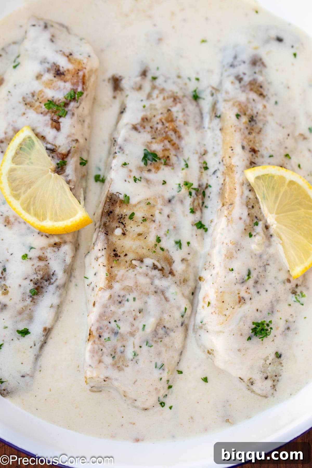 Silken Fish Delight 12 Cooked fish in white sauce served with fresh lemon slices and a sprinkle of herbs.