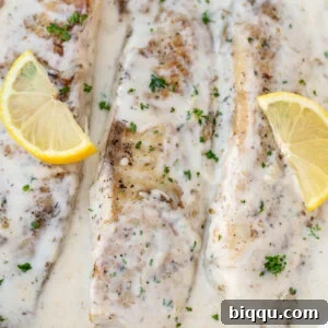 Fish in white sauce with lemon slices, showcasing the creamy texture and fresh garnish.