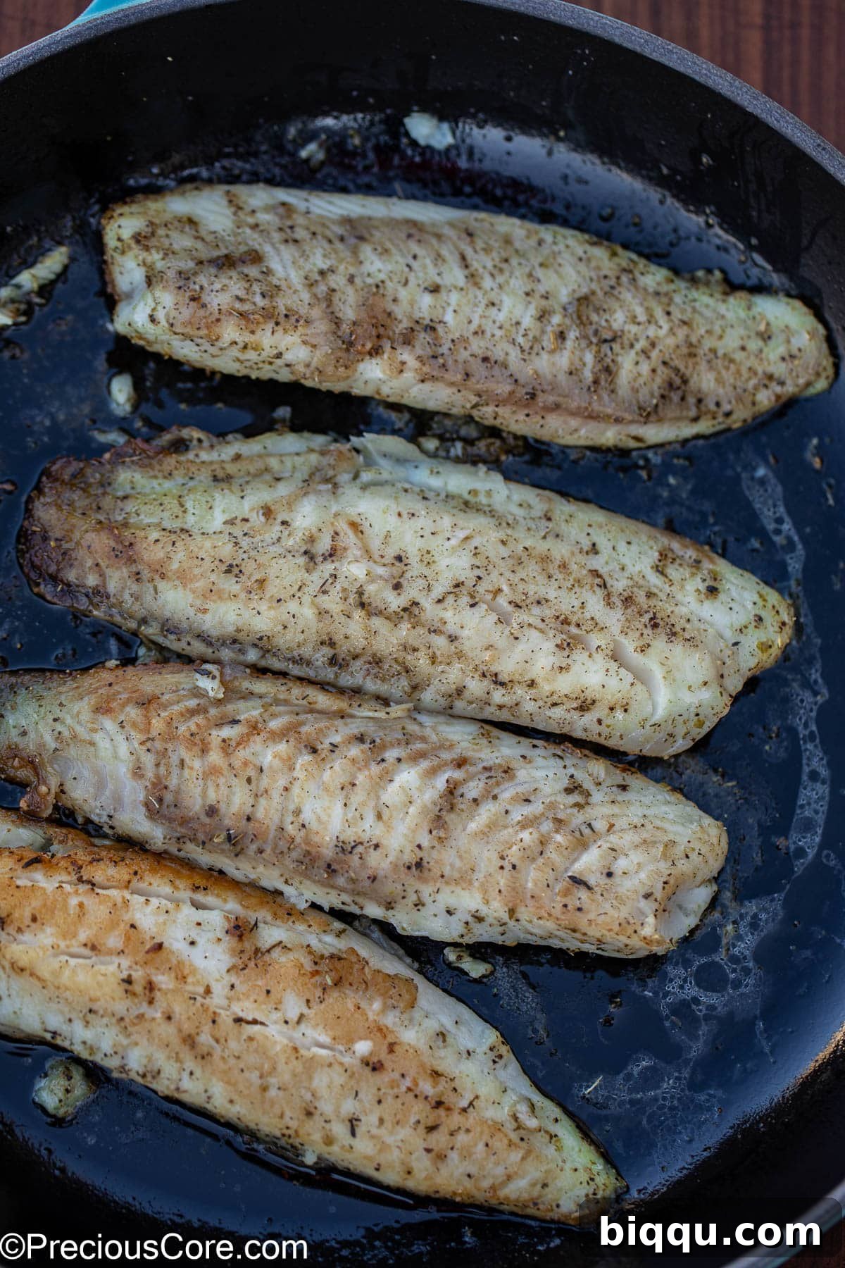 Silken Fish Delight 6 Seasoned tilapia fillets searing in olive oil in a large skillet, developing a golden crust.