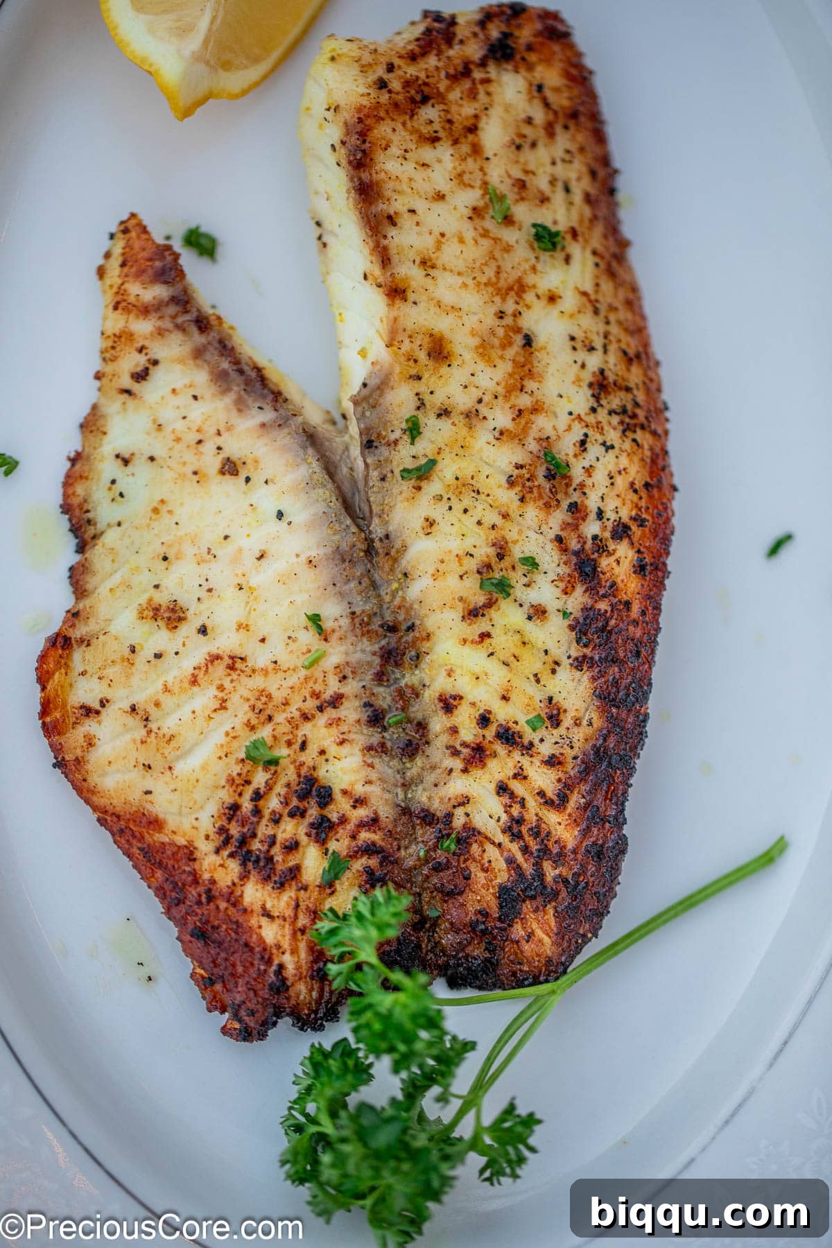 A cooked fish fillet garnished with minced parsley.