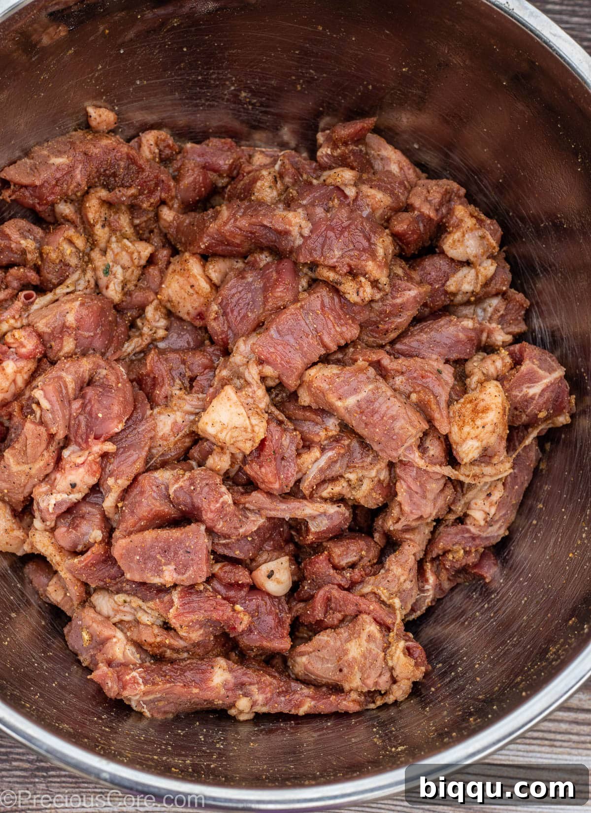 Seasoned bite-sized pieces of beef in a stainless steel bowl.