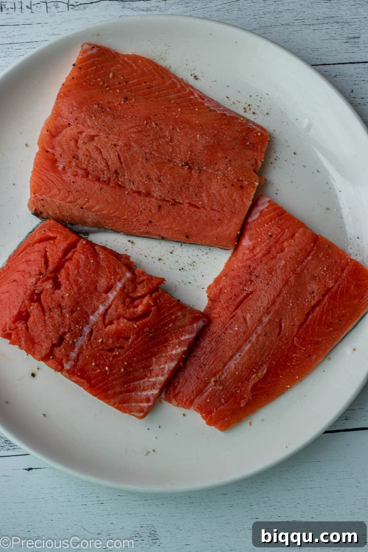 Salmon fillets seasoned with salt and pepper, ready for cooking.