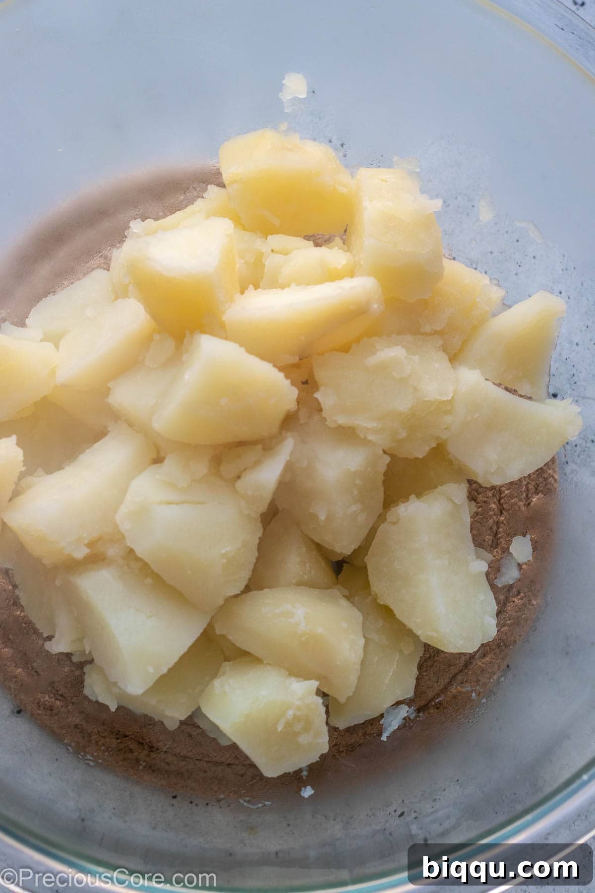 Uniformly diced potatoes boiling gently in a pot on the stovetop, ensuring even cooking.