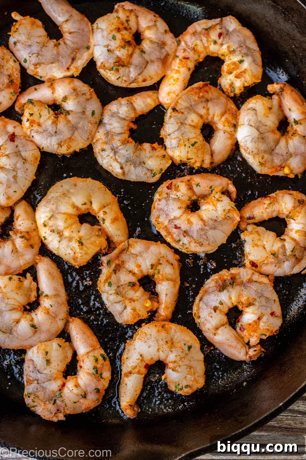 Perfectly seasoned shrimp arranged in a single layer within a sizzling 12-inch cast iron skillet, ready for searing.