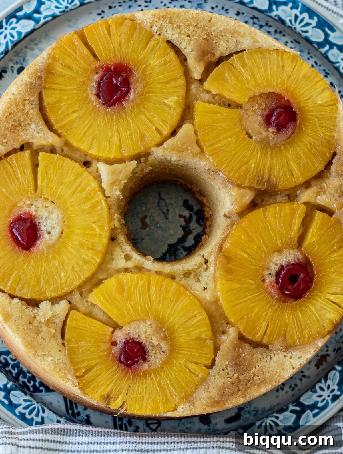 A perfectly round Pineapple Upside Down Pound Cake, showcasing its golden-brown crust and fruit topping.