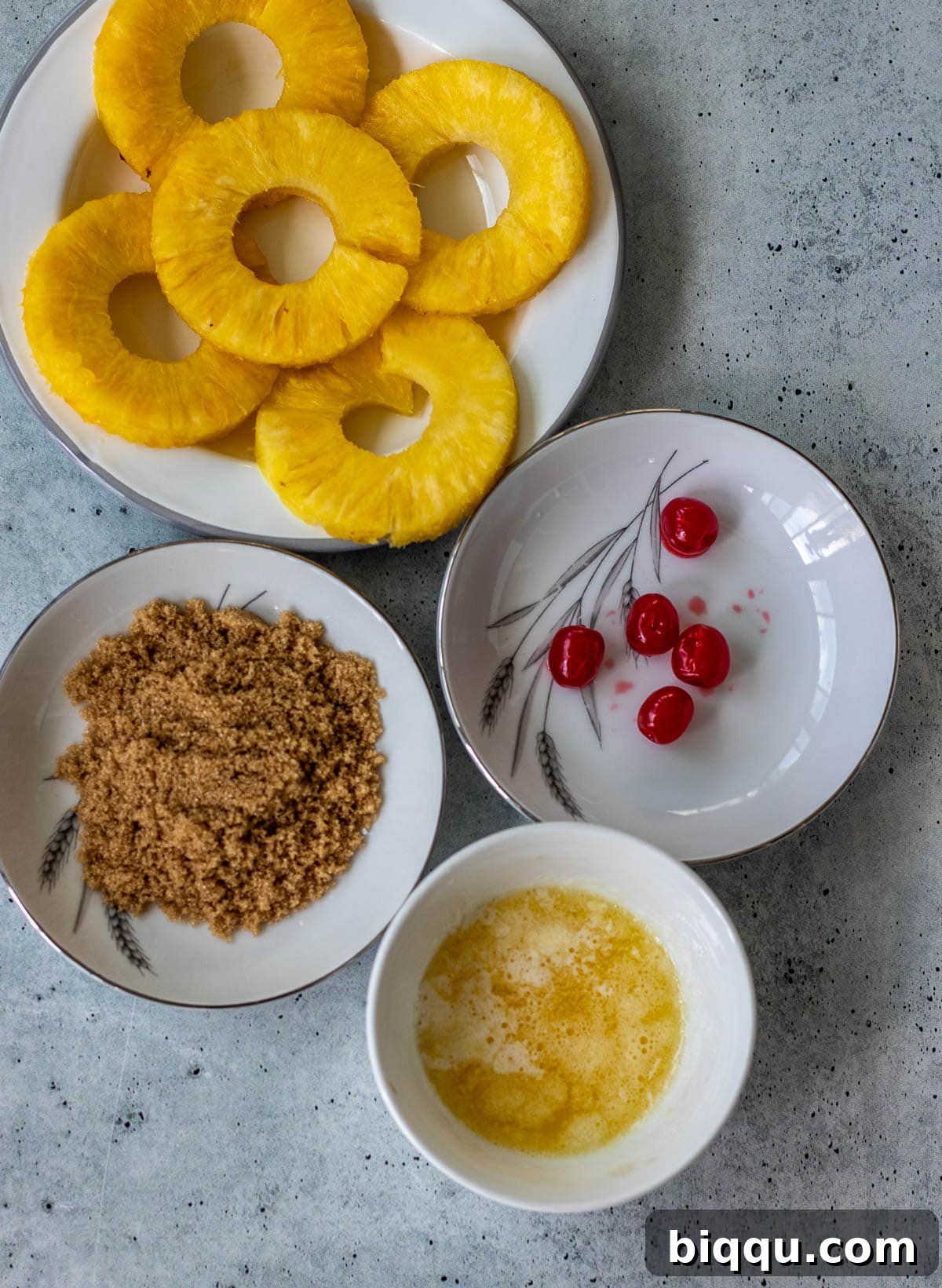 Pineapple rings, maraschino cherries, light brown sugar, and melted butter, ready for the cake topping.