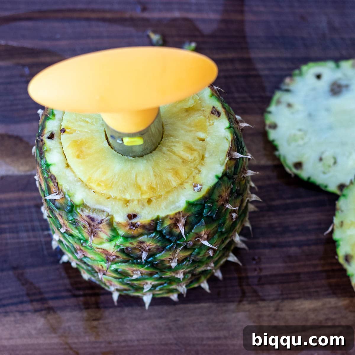 A pineapple corer shown inside a fresh pineapple, illustrating how to prepare fresh pineapple rings.