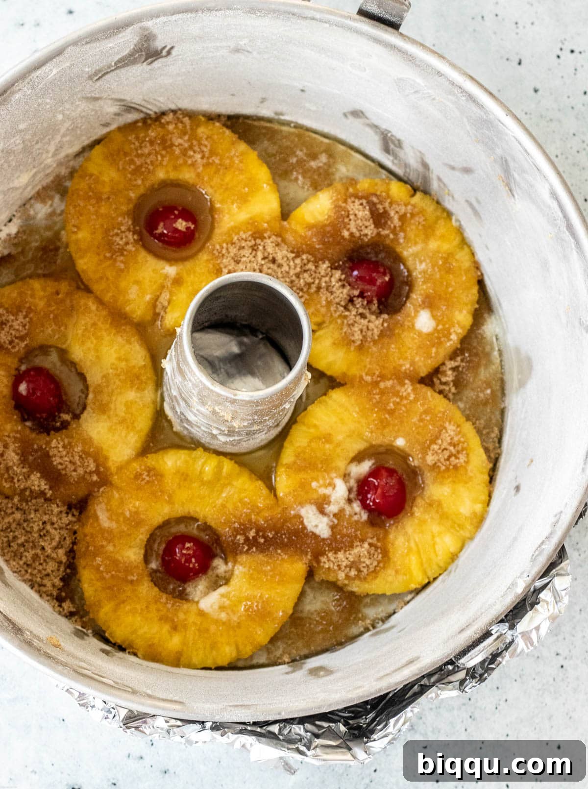 Baking pan with its bottom covered in pineapple rings, maraschino cherries, brown sugar, and melted butter, ready for batter.