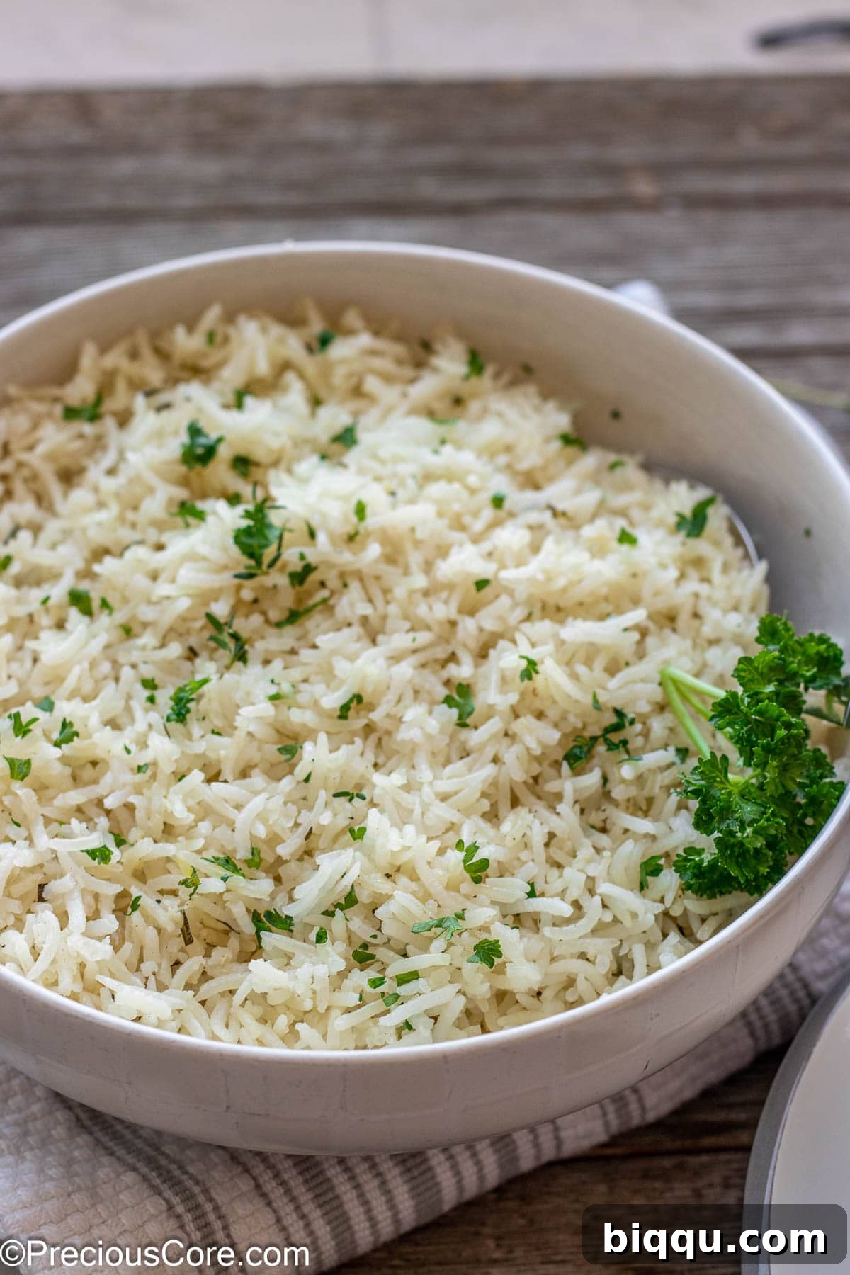 A glistening bowl of freshly cooked garlic herb rice, generously topped with vibrant minced fresh parsley, ready to be served and enjoyed.