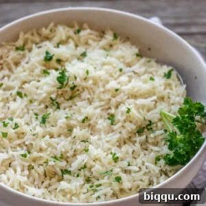 A bowl of garlic herb rice topped with vibrant minced fresh parsley, showcasing its fluffy texture and inviting aroma.