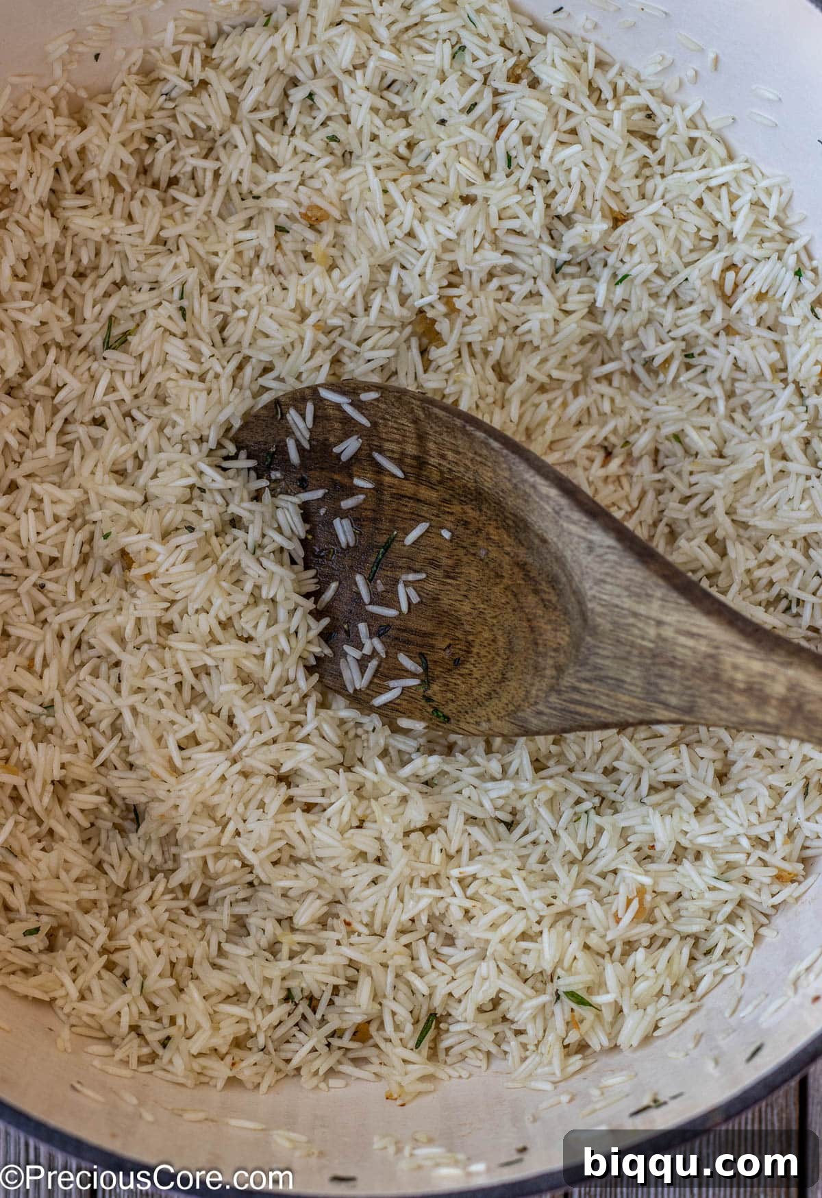 Lightly toasted Basmati rice grains, perfectly golden and aromatic, being gently stirred in a pot, absorbing the rich flavors of sautéed garlic and herbs, preparing for the liquid addition.