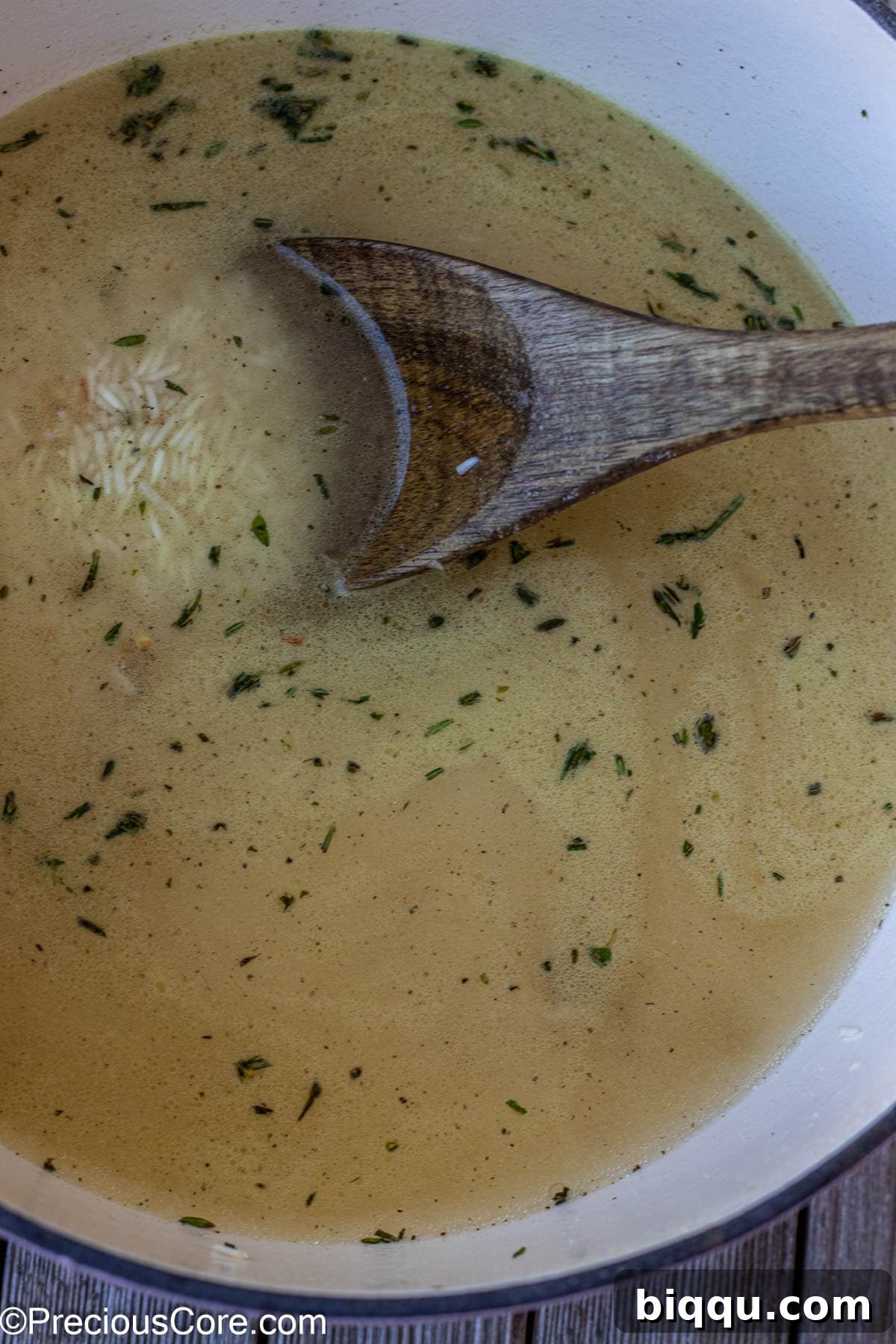 Fresh water and essential seasonings, including chicken bouillon powder, salt, and black pepper, being carefully added to the toasted rice in the pot, ready for absorption and flavor infusion.
