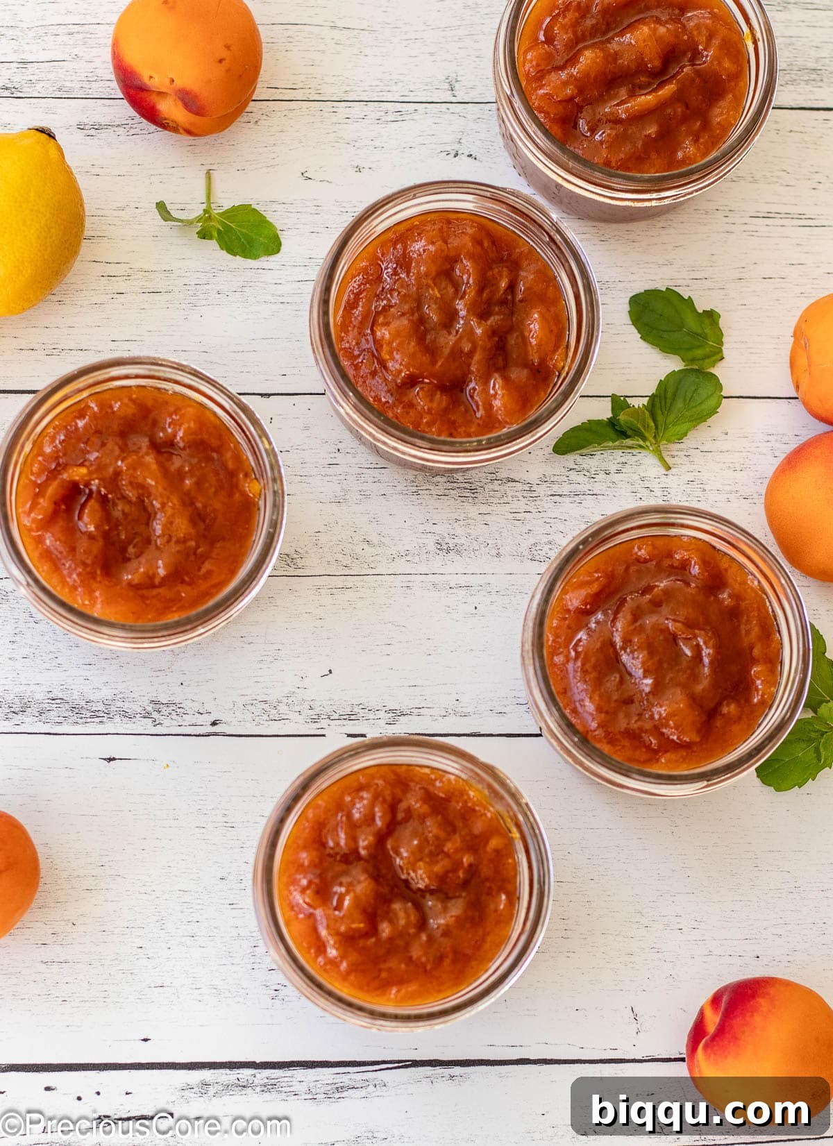 5 open jars filled with apricot preserves.